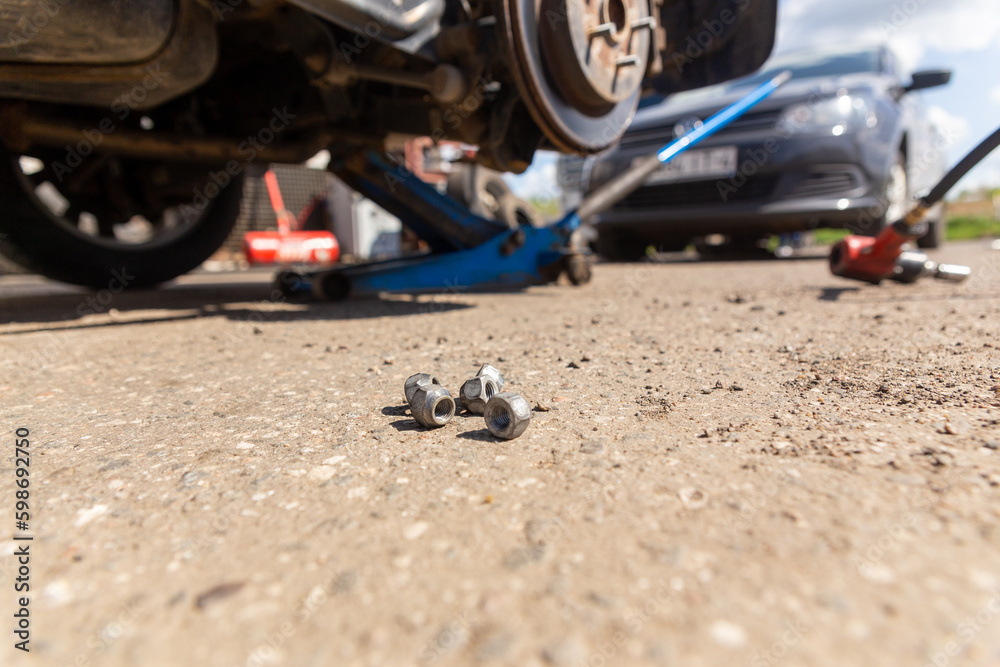 Car on tire mounting with removed wheel on pneumatic jack, seasonal tire change, car service concept. Car on tire mounting with removed wheel on pneumatic jack, seasonal tire change, car service concept.