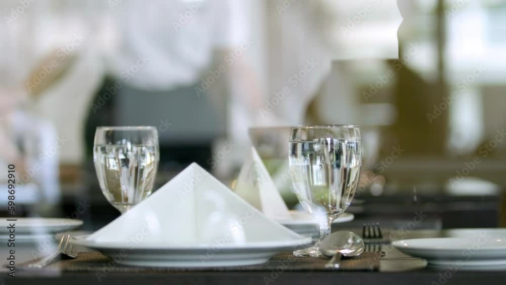 Dining table in a restaurant ready to welcome guests, full glass of water and spoon, 2 video clips Dining table in a restaurant ready to welcome guests, full glass of water and spoon, 2 video clips