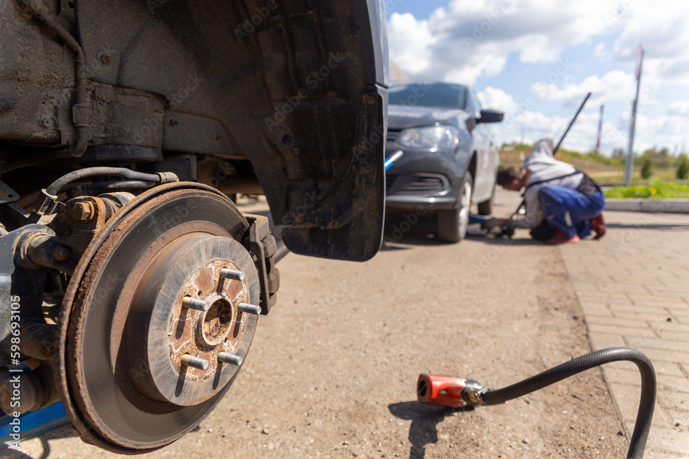 Car on tire mounting with removed wheel on pneumatic jack, seasonal tire change, car service concept. Car on tire mounting with removed wheel on pneumatic jack, seasonal tire change, car service concept.