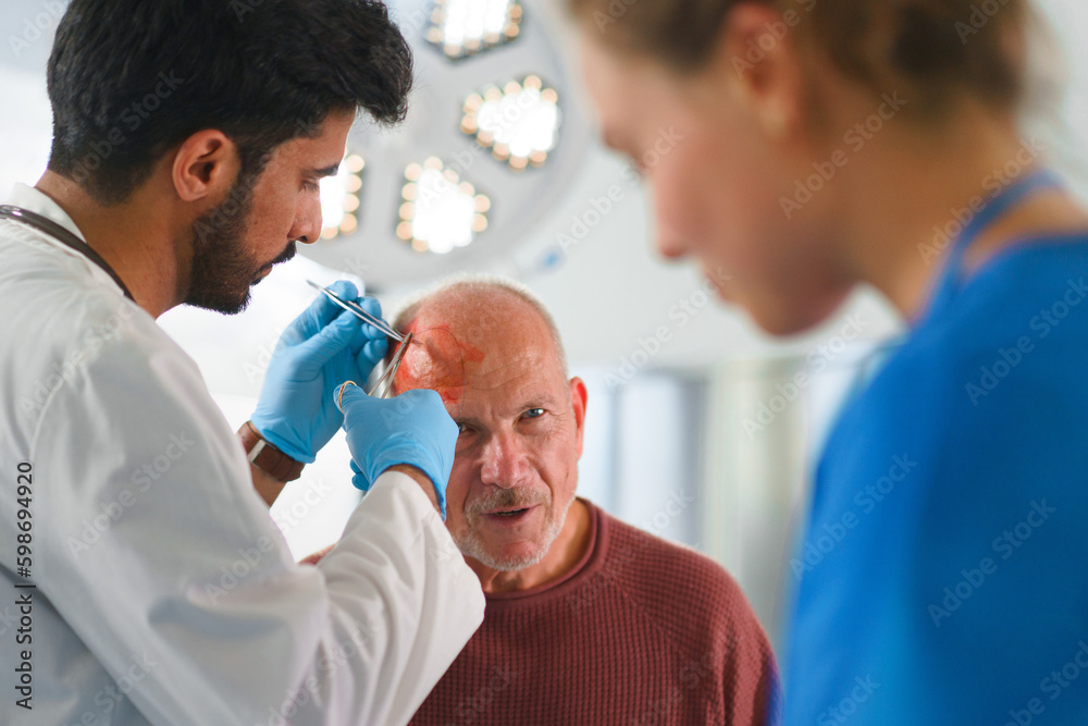 Close-up of doctor and nurse treating injury of senior man. Close-up of doctor and nurse treating injury of senior man.