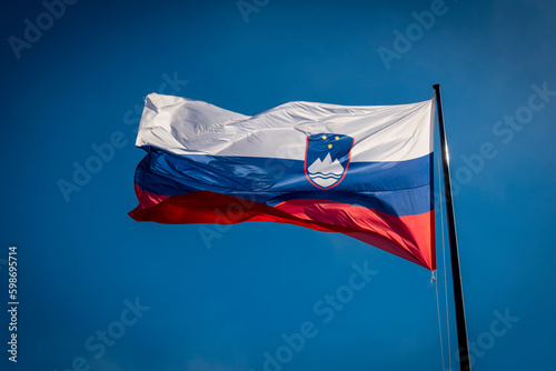 Slovenian flag fluttering against a clear blue sky
