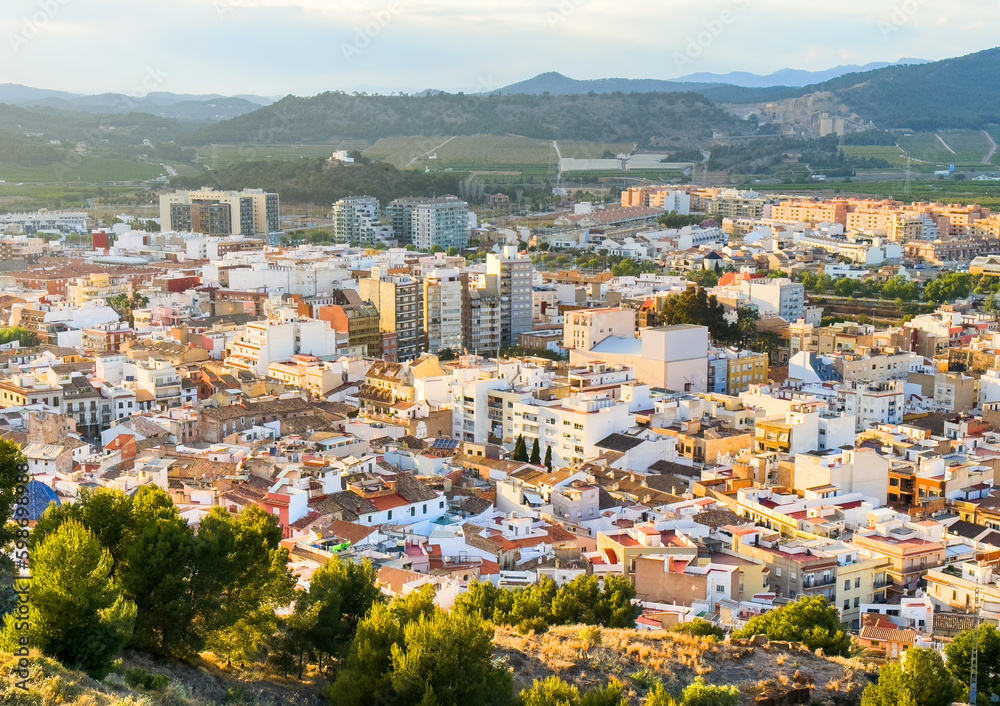 Buildings, houses and streets in city, aerial view. View of rooftops and streets of city of Sagunto in Spain. Town against backdrop of mountains. Roofs of houses and roofs from side of Sagunto Castle.