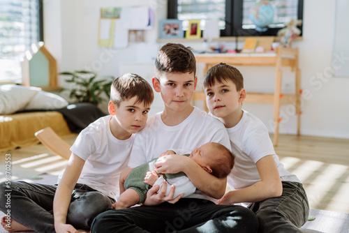 Three big brothers with their little newborn brother.
