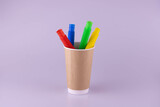 Colorful toy tubes in a brown paper cup