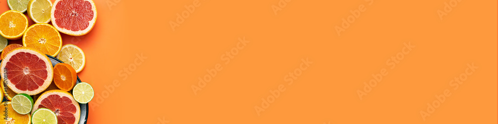 Fresh, Fruity and juicy fruit concept with free text space, web banner. Flat layout with various fresh cut citrus fruits on the left side of the picture on an orange background