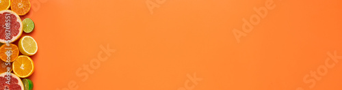Fresh, Fruity and juicy fruit concept with free text space, web banner. Flat layout with various fresh cut citrus fruits on the left side of the picture on an orange background