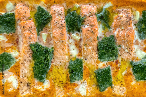 Low carb salmon fillet with spinach and mozzarella in creamy sauce freshly baked in the oven, Closeup. photo