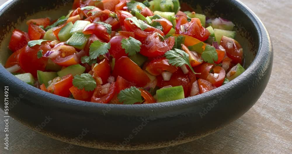 Pico de Gallo salsa in a bowl. Traditional Mexican cuisine dish with tomato, cucumber, onion and fresh coriander. Table spin.