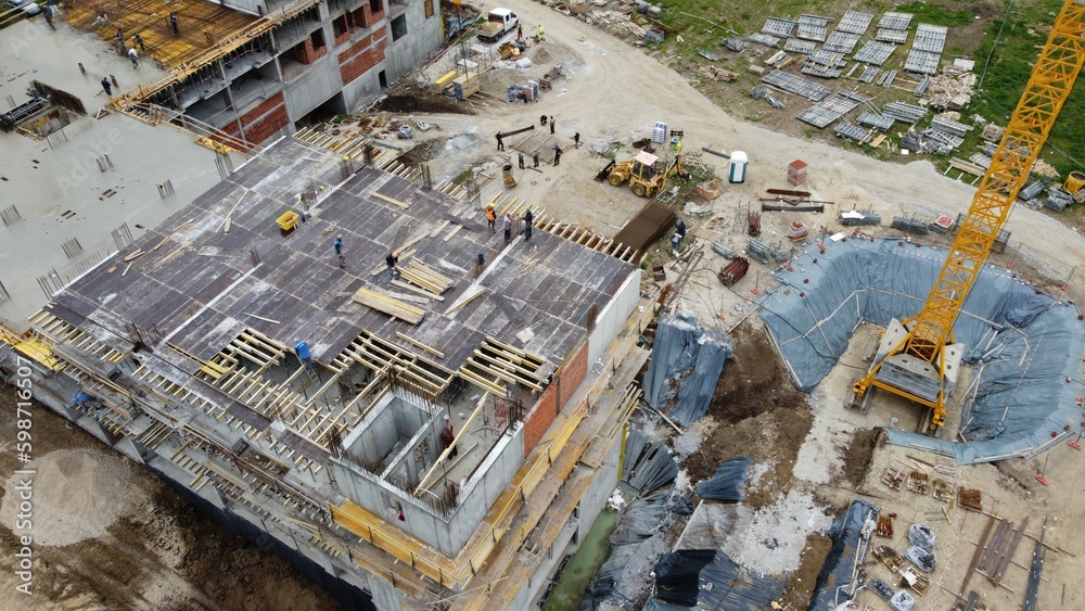 Aerial view of residential and commercial construction site, concrete truck mixers dump cement mixture to pour third floor slab