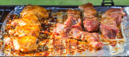 Barbecued Chicken Thighs and Country Style Ribs on a grill covered with aluminum foil hot and ready to be plated. photo