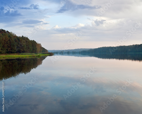 Autumn misty evening lake with grove on shore