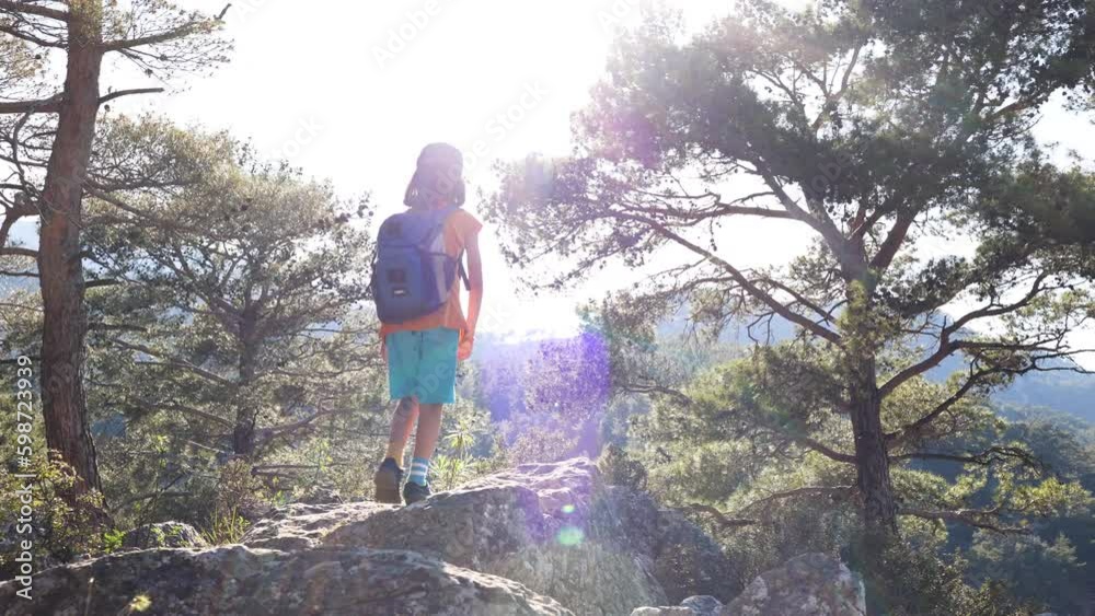 Adventure and travel. a little boy with a backpack walks along a forest path against the backdrop of mountains and a blue sky. trips with children. child in the forest. Adventure and travel. a little boy with a backpack walks along a forest path against the backdrop of mountains and a blue sky. trips with children. child in the forest.
