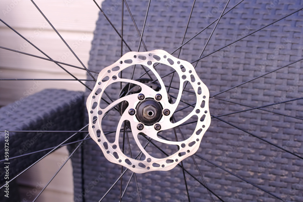 Bicycle disk brake rotor plate on bicycle wheel close up photo. Repairing bike at home. Sporting goods. Active lifestyle concept. Athletic equipment.