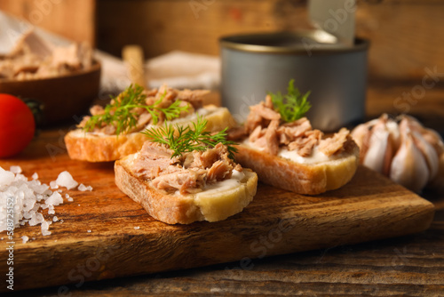 Board with delicious tuna bruschettas on wooden table