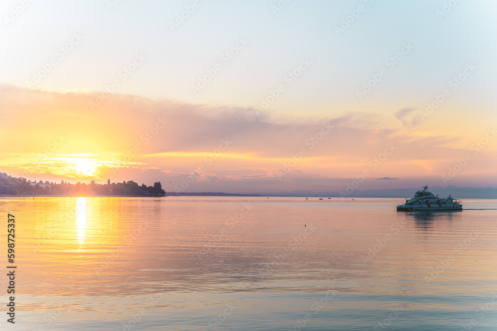 Beautiful sunrise view from Imperia statue at harbor entrance with catamaran ferry on lake Constance in early morning hours. Steamer harbor, Constance, Baden-Württemberg, Germany, Europe.