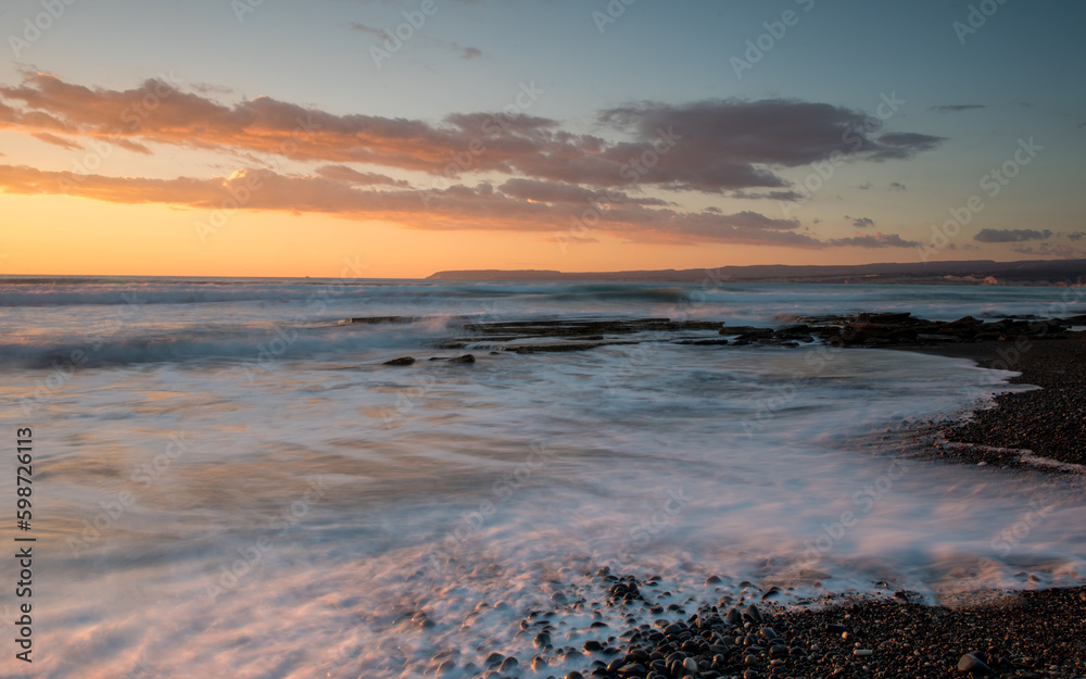 Dramatic beautiful sunset on a rocky coast. Bright sun light on the horizon