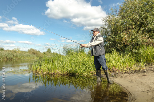 Angler stands in the water and casts a spinning rod.