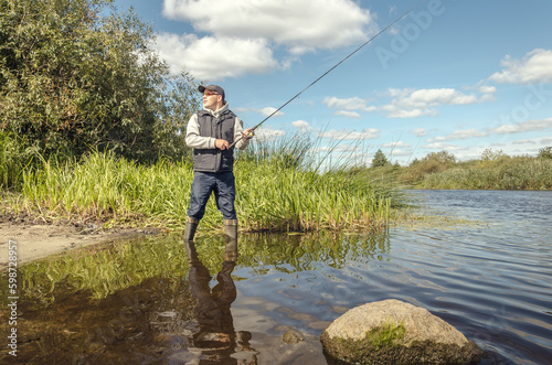 Fisherman in a hat on the river bank