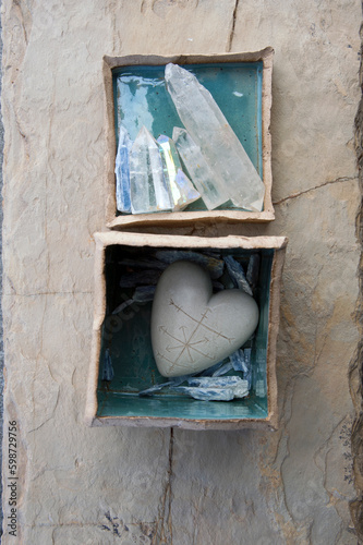 Still Life Photography of a stone heart etched with an abstract map with crystal Kyanite in an earthen box. 
