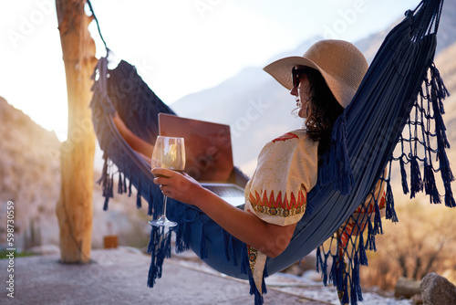young nomad woman in a hammock with a laptop holding a glass of wine relaxed in Elqui Valley photo