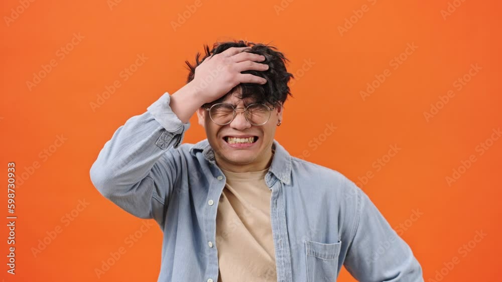 Confused Asian man puts hands on head with scared expression Confused Asian man puts hands on head with scared expression