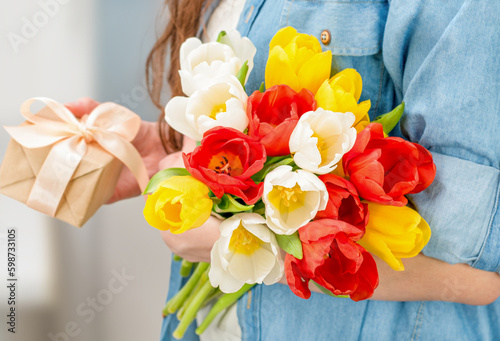 woman with a bouquet of tulips and a gift box in her hands close-up