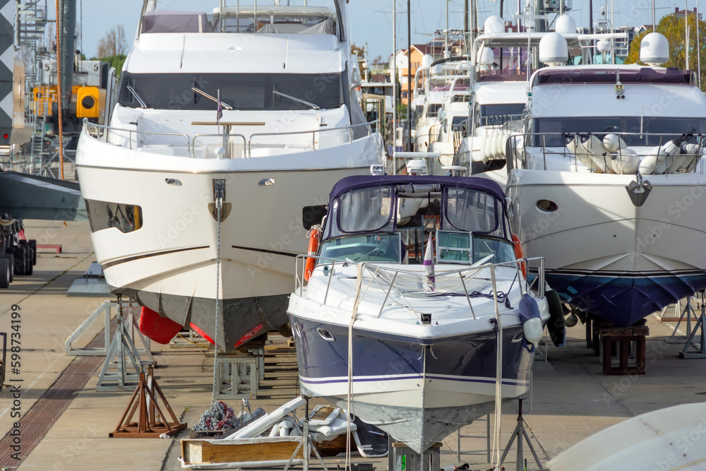 Fototapeta premium Marine vessels and offshore storage installations on land, servicing yachts, boats other ships in docks pier. Freight industry, maritime transport.