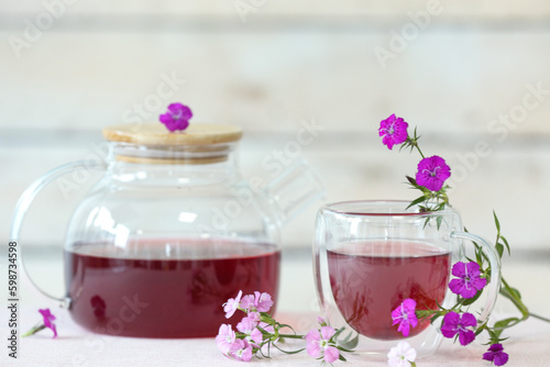 Pretty tea set with delicate flowers on white table near wooden wall