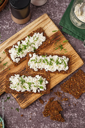 Wooden board with tasty cottage cheese and rye bread on grey grunge background