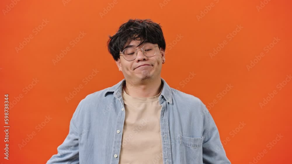 Asian man in glasses shows thumbs down in disapproval Asian man in glasses shows thumbs down in disapproval