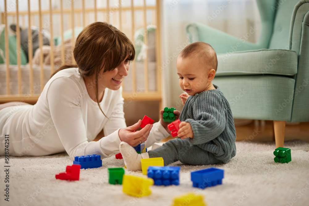 Mother and her baby boy playing with colored toy blocks at home Mother and her baby boy playing with colored toy blocks at home