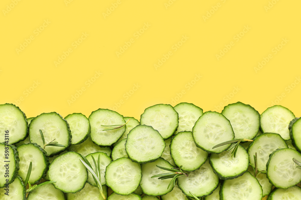 Slices of cucumber with rosemary on yellow background Slices of cucumber with rosemary on yellow background