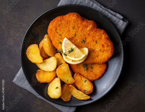 фотографія Chicken schnitzel with sauce, fried potatoes and lemon in a plate