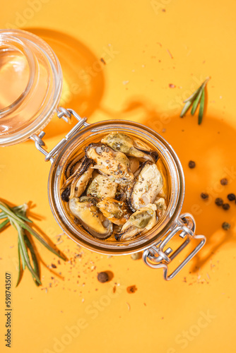 Jar with pickled mussels on orange background