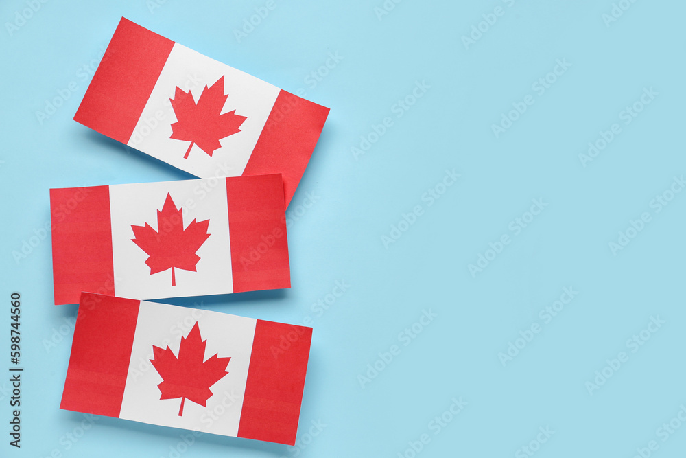 Paper flags of Canada on blue background