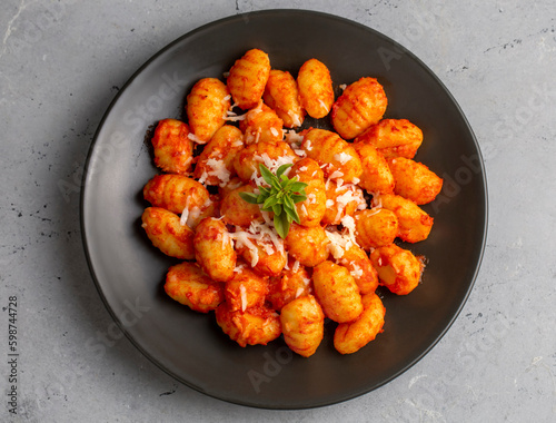 Traditional Italian food potato gnocchi with tomato sauce, parmesan cheese and fresh basil on dark table. Top view. Healthy food.