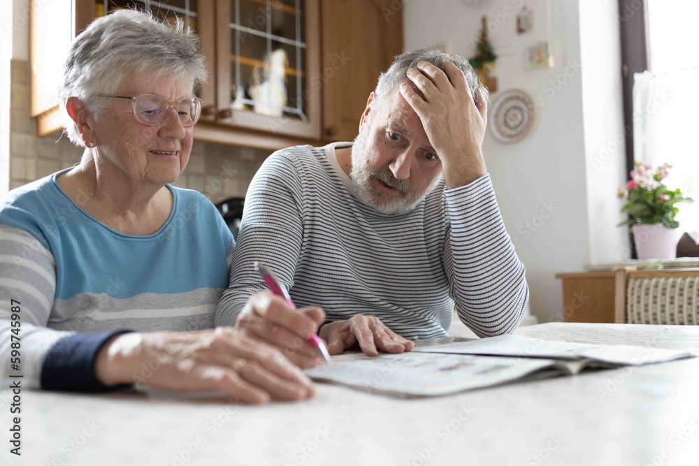 Grey haired senior couple making sudoku in the kitchen Grey haired senior couple making sudoku in the kitchen