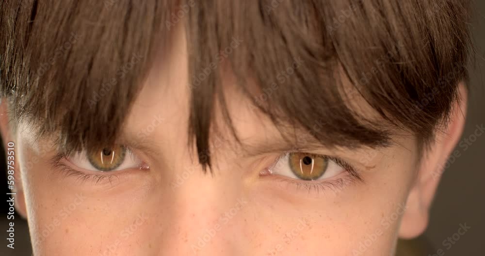 Closeup of a teenager boy blinking eyes. He blinks frequently, tired