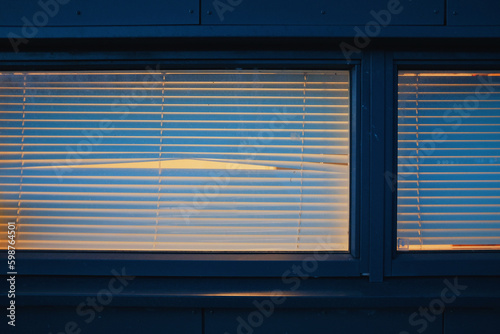 empty window with blinds and peephole at night