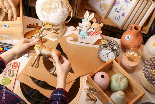 Woman holding toy deer near table with many different stuff, above view. Garage sale
