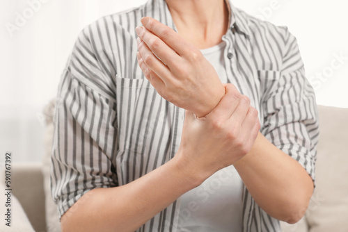 Woman suffering from pain in hand indoors, closeup. Arthritis symptoms