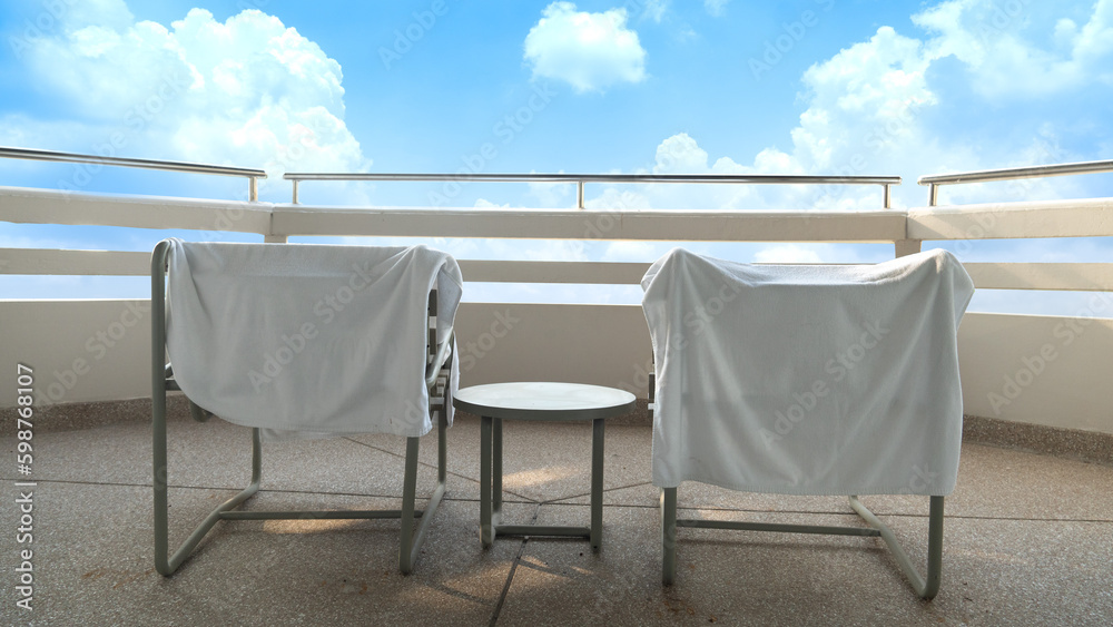 Rat cloth covering the chair to sit and enjoy the view. On the fence of the building behind the room made of cement and round steel. Under blu sky and white clouds.