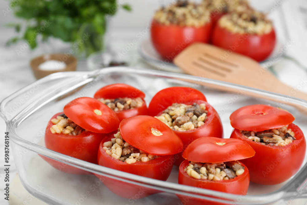 Delicious stuffed tomatoes with minced beef, bulgur and mushrooms in glass baking dish, closeup Delicious stuffed tomatoes with minced beef, bulgur and mushrooms in glass baking dish, closeup