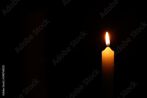 One burning candle on black background, space for text