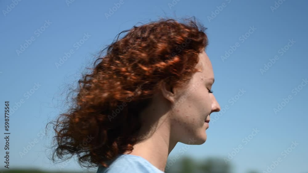 Portrait of a red-haired curly woman against the blue sky. Video 360 degrees. Generative AI Portrait of a red-haired curly woman against the blue sky. Video 360 degrees. Generative AI