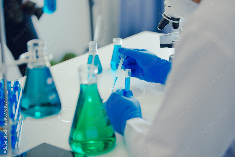 medical or scientific researcher researching and experimenting Multi-colored solution, vial and microscope In the laboratory or in the laboratory by wearing blue gloves and white clothing completely. medical or scientific researcher researching and experimenting Multi-colored solution, vial and microscope In the laboratory or in the laboratory by wearing blue gloves and white clothing completely.