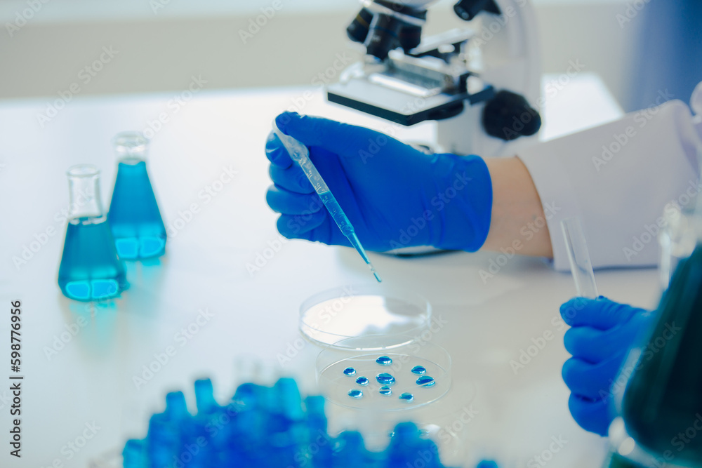 medical or scientific researcher researching and experimenting Multi-colored solution, vial and microscope In the laboratory or in the laboratory by wearing blue gloves and white clothing completely. medical or scientific researcher researching and experimenting Multi-colored solution, vial and microscope In the laboratory or in the laboratory by wearing blue gloves and white clothing completely.