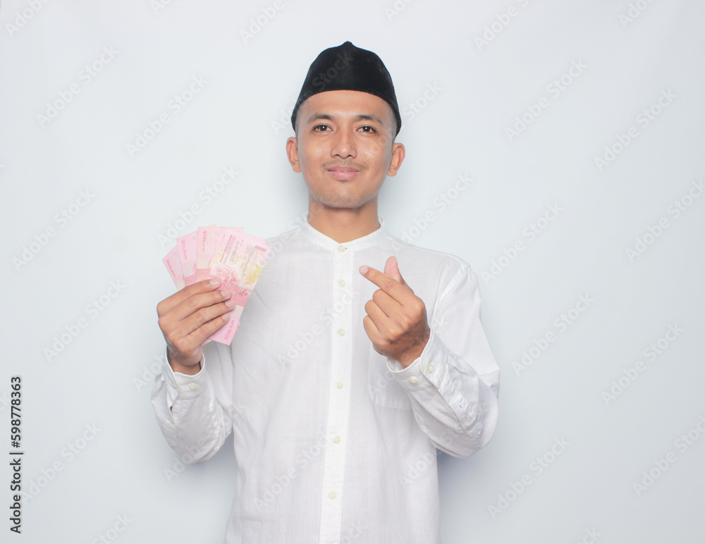 Asian muslim man holding money isolated on white background. Ramadan and eid mubarak concept. Asian muslim man holding money isolated on white background. Ramadan and eid mubarak concept.