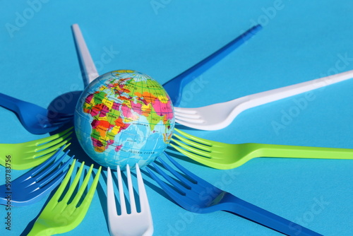 Earth mockup surrounded by disposable plastic forks.	