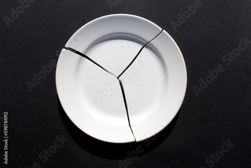 Bild auf Leinwand A broken white plate lies on a black background.